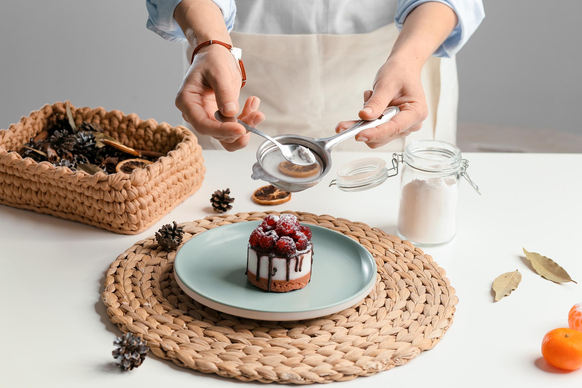 Hands arranging colorful plated dessert on rustic table